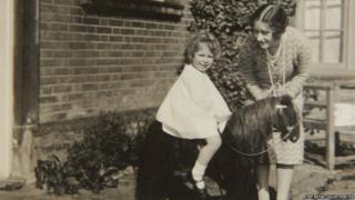 Previously unpublished family photograph issued by the Royal Collection of Queen Elizabeth II with a toy horse in front of Naseby Hall 1928.