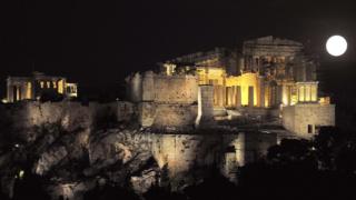Full moon rises next to the ancient Acropolis in Athens