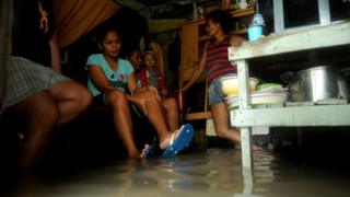 A family sit inside their flooded house, south of Manila in the Philippines