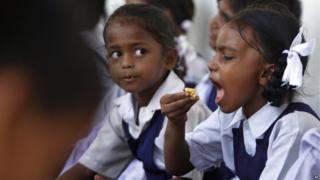 An Indian schoolgirl eats a free midday meal at school on the outskirts of the city of Jammu.