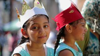 Two young girls watch on at the festival, they are wearing paper crowns