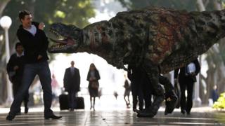 A man reacts as a performer dressed in a Tyrannosaurus rex dinosaur costume walks next to him during a publicity event in central Sydney, Australia.