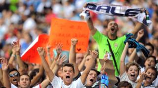 Real Madrid fans wave and cheer in the stadium