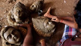 An artisan works on clay idols of the Hindu god Vishwakarma