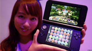 A girl holds a Nintendo 3DS displaying Puzzle and Dragons Z
