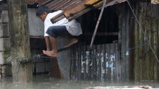 Boy climbs out of the window as flood water rises.