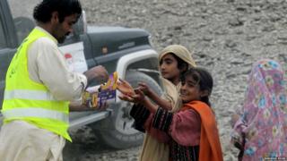 A Pakistani volunteer distributes biscuit to earthquake survivors