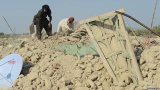 Pakistani earthquake survivors search for their belongings in the rubble of collapsed mud houses