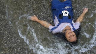 A girl plays in a flooded street in Thailand