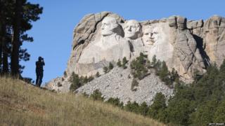 A tourist takes a picture of Mount Rushmore National Memorial
