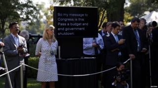 A teleprompter used by U.S. President Barack Obama to deliver remarks on the implementation of the Affordable Care Act is shown among White House staff and journalists is seen in the Rose Garden of the White House in Washington, October 1, 2013. The U.S. government began a partial shutdown on Tuesday for the first time in 17 years, potentially putting up to 1 million workers on unpaid leave, closing national parks and stalling medical research projects.