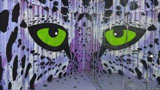 striking pair of green eyes in tower block art project Tour 13 in Paris