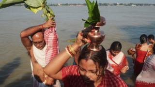 Indian Hindu devotees perform rituals with a banana tree wrapped in a sari, symbolising the wife of Hindu god Ganesha, near the river Ganges during the Durga Puja festival in Kolkata.