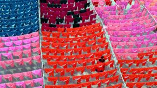 Worker hanging up brightly coloured clothes
