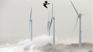 The stormy winds reach France and waves crash against wind turbines