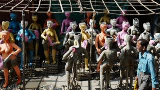 In India a man walks past the half-finished clay idols of Hindu mythological characters "Dakinis" and "Yoginis"