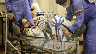 Astronaut in spacesuit getting strapped into position