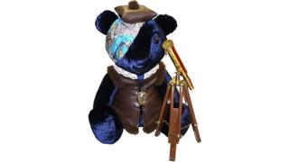 A blue bear with a telescope and atlas-styled bandana.