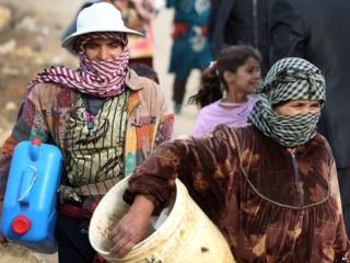 Two women carrying water containers