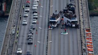 Bridge with Tiger woods hitting golf balls surrounded by cars watching.