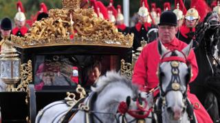 Queen with South Korean president in a carriage surrounded by horses.