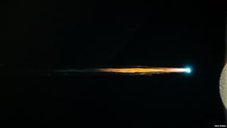 An ATV travels through space showing a long burning tail of debris