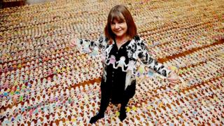 Julia Donaldson holding a row of paper dolls