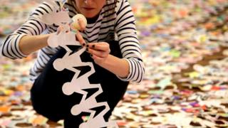 Volunteer using sticky tape on a paper doll