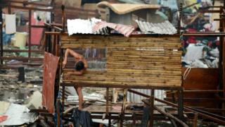 A man reconstructs his destroyed house in Tacloban, eastern island of Leyte in November 12, 2013. The Philippine government said it had deployed armoured vehicles, set up checkpoints and imposed a curfew to help end looting in a city devastated by Super Typhoon Haiyan. Tacloban - on the central island of Leyte