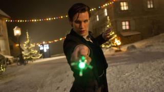 Matt Smith as the Doctor pointing his glowing green sonic screwdriver at the camera.