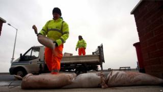 A council worker piles sandbags in front of a building