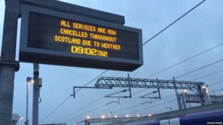 Train station sign reading 'all services now cancelled'.