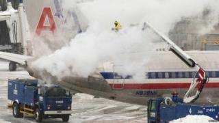 An American Airlines crew member sprays de-icing solution on a plane during a winter north eastern snow storm in Boston, Massachusetts January 2, 2014.