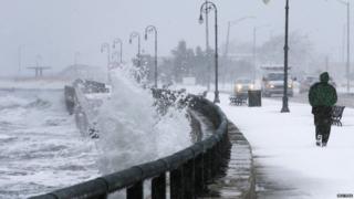 A man jogs past waves crashing against the seawall around high tide during a winter nor"easter snowstorm in Lynn, Massachusetts January 2, 2014.