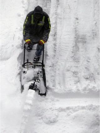 man clearing snow in parking lot