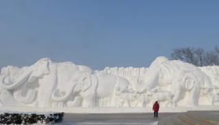 A giant snow sculpture shows elephants in a line