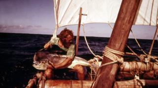 Mike Fitzgibbons holding a large fish, on the raft at sea