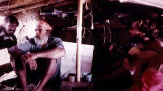 Three crew members inside one of the cabins - one is holding a guitar