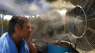 A tennis fan tries to cool off from the heat.