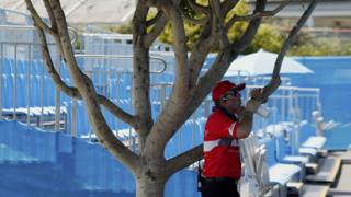 A security guard has a drink in the shade next to an empty stand after play was suspended at the Australian Open 2014 tennis tournament