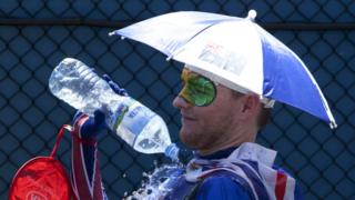 A spectators pours water over himself to cool down