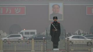 A Chinese policeman stands surrounded by thick smog in Beijing