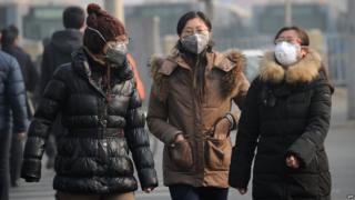 A group of women wear face masks as they make their way along a street in Beijing on January 16, 2014.