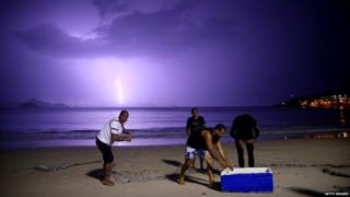 Fishermen on Copacabana Beach during a lightning strike