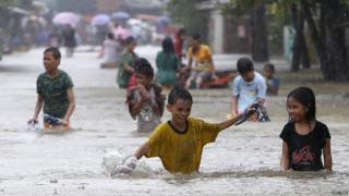 Residents in the Philippines wade through a flooded road to reach higher ground to try to escape flood waters.