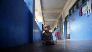 Boy resting in the corridor of a school turned into an evacuation centre.
