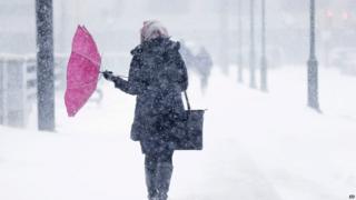 A pedestrian's umbrella is turned inside out during a winter snowstorm
