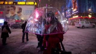woman carrying an umbrella walks along 7th Avenue at Times Square during a snow storm in New York January 21, 2014. A
