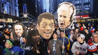 Fans hold up posters of Seattle Seahawks head coach Pete Carroll, quarterback Russell Wilson, running back Marshawn Lynch, and cornerback Richard Sherman.