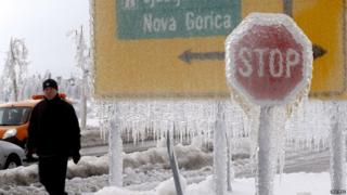 A man walks next to ice-covered road signs in Postojna February 3, 2014